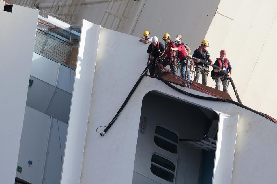 Salvage crew workers work on a side of the capsized Costa Concordia cruise liner outside Giglio harbour September 16, 2013. Salvage engineers pushed back the start of an operation on Monday to lift the wrecked liner upright after an overnight storm interrupted preparations, officials said. The so-called "parbuckling" operation will see the ship rotated by a series of cranes and hydraulic machines, pulling the hulk from above and below and slowly twisting it upright. REUTERS/Tony Gentile (ITALY - Tags: DISASTER MARITIME SOCIETY)