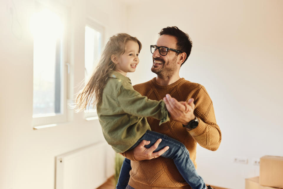 Adult holding and playing with a child indoors, both smiling