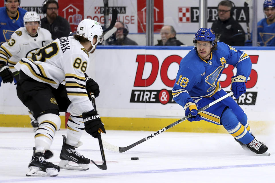 St. Louis Blues' Robert Thomas (18) controls the puck while under pressure from Boston Bruins' David Pastrnak (88) during the second period of an NHL hockey game Saturday, Jan. 13, 2023, in St. Louis. (AP Photo/Scott Kane)