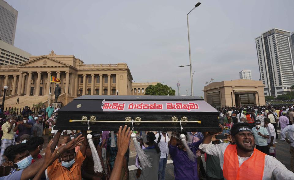 Supporters of Sri Lanka's main opposition shout slogans as they carry a coffin pasted with the name of Finance Minister Basil Rajapaksa during a protest outside the president's office in Colombo, Sri Lanka, Tuesday, March 15, 2022. The protestors were demanding the resignation of President Gotabaya Rajapaksa as the country suffers one of the worst economic crises in history. (AP Photo/Eranga Jayawardena)