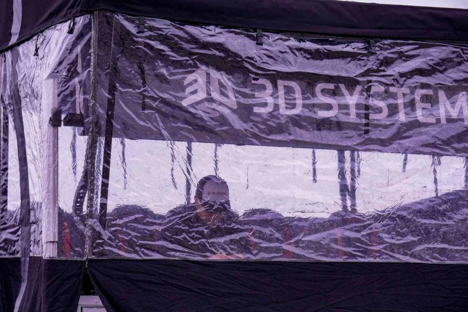 A crew member shelters from the drizzle and cold weather at Charlotte Motor Speedway. Jim Dedmon-USA TODAY Sports