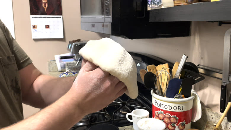 Person stretching pizza dough