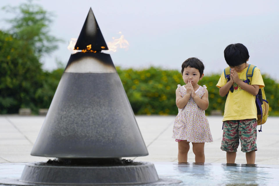 Children pray in front of the "Peace of Fire" at the Peace Memorial Park in Itoman, Okinawa, Japan, Tuesday, June 23, 2020. Okinawan people find it unacceptable that their land is still occupied by a heavy U.S. military presence even 75 years after World War II. They have asked the central government to do more to reduce their burden, and Japanese Prime Minister Shinzo Abe's government repeatedly say it is mindful of their feelings, but the changes are slow to come. (Koji Harada/Kyodo News via AP)