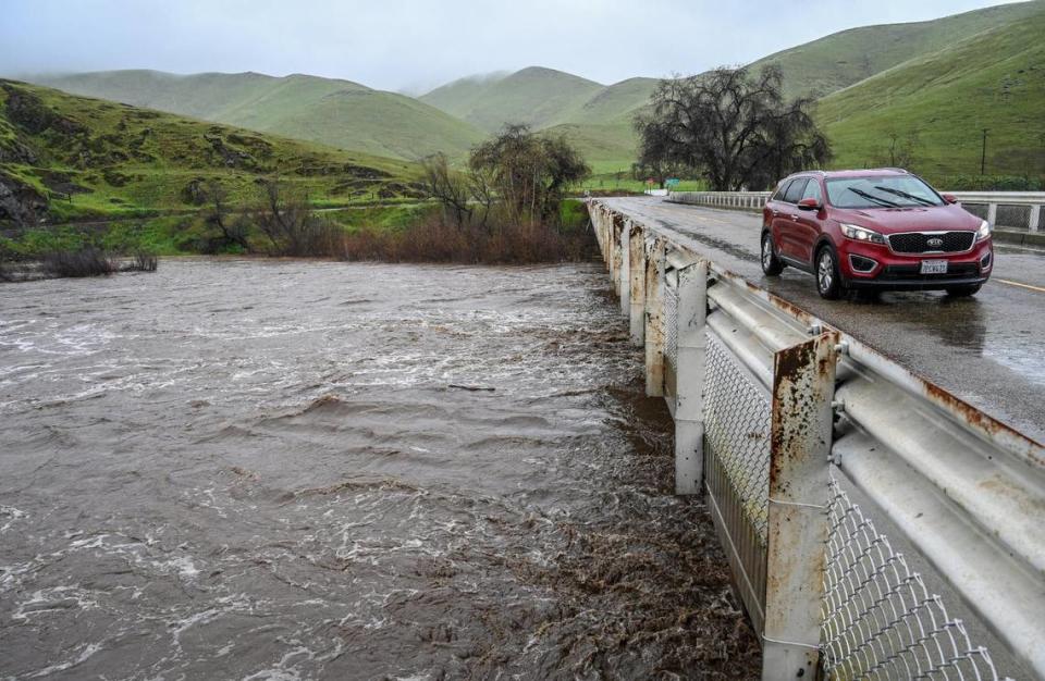 A car passes over the bridge at Piedra Road and Trimmer Springs Road as the Kings River swells within its banks in eastern Fresno County on Friday, March 10, 2023.