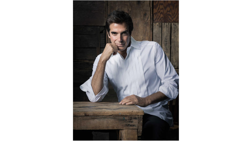 a man in a white shirt sits at a wooden table