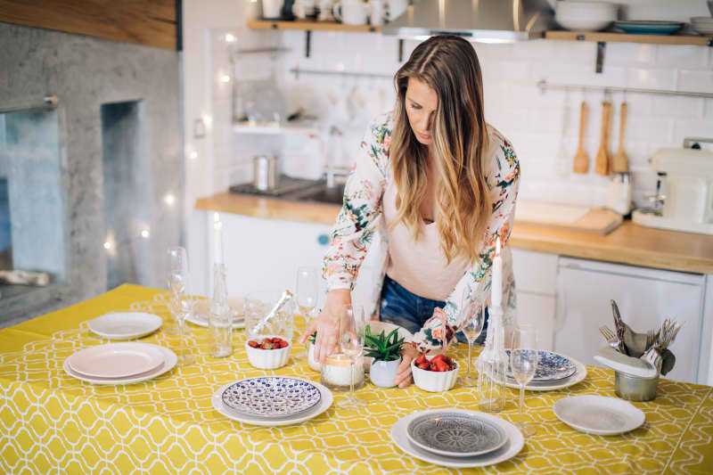 Woman arranging table for home dinner with friend or family.