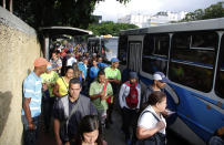 People stand in a bus line in Caracas, Venezuela, Tuesday, July 23, 2019. The lights were returning to life early Tuesday across Venezuela following a massive blackout a day earlier that crippled communications, froze the Caracas metro and snarled rush hour traffic, officials said. (AP Photo/Leonardo Fernandez)