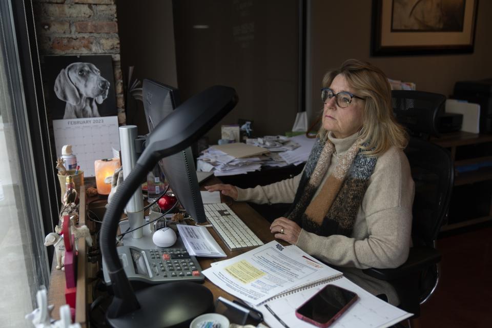 Leslie Allison-Seei, who runs a small promotion and sweepstakes management company with her husband, works on her computer at their office Wednesday, Feb. 15, 2023, in Villa Park, Illinois. Expansive paid leave legislation requiring Illinois employers to give workers paid time off based on hours worked, to be used for any reason, is ready for action by Democratic Gov. J.B. Pritzker. Allison-Seei is supportive of her employees but said it's hard to compete with corporate paid time off policies. (AP Photo/Erin Hooley)