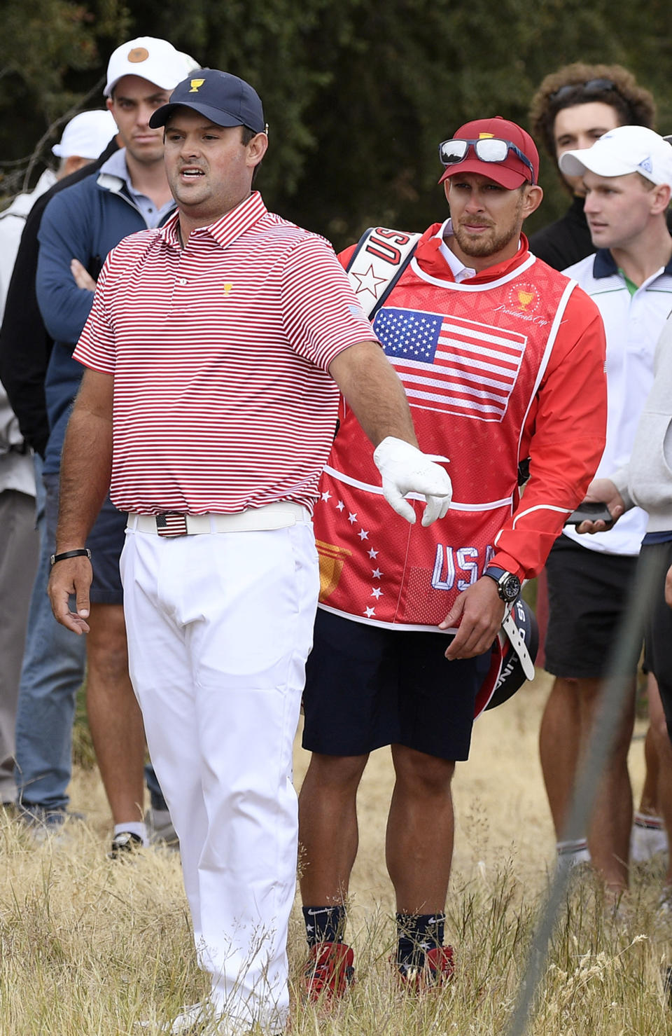 In this Dec. 12, 2019, photo U.S. team player Patrick Reed and his caddie, Kessler Karain, right, look for a potential shot during the President's Cup golf tournament at Royal Melbourne Golf Club in Melbourne. Karain, the brother-in-law of Reed, will not be on the bag for the final session of the Presidents Cup after shoving a spectator Saturday, Dec. 14, 2019. (AP Photo/Andy Brownbill)