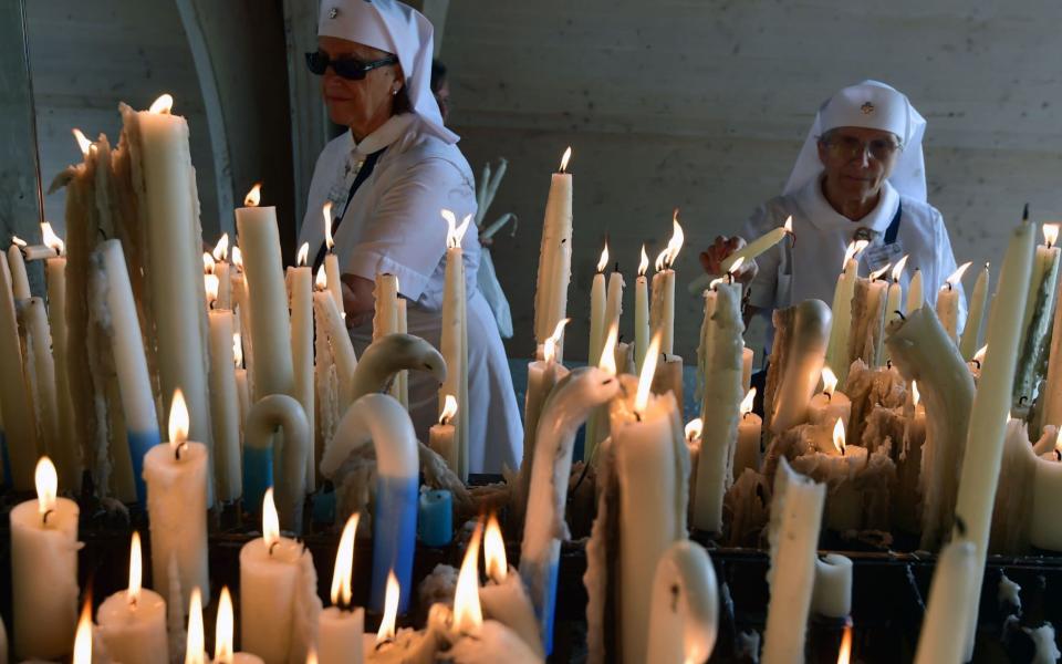 Catholic nuns light candles during their pilgrimage to Lourdes - AFP