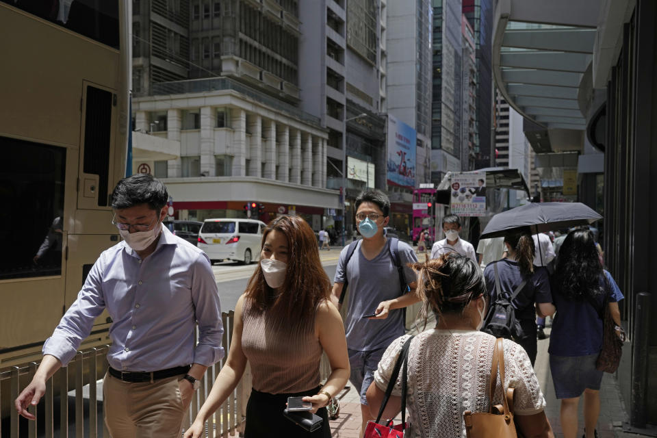 People wearing face masks walk on a street in Hong Kong, Tuesday, July 12, 2022. Hong Kong's leader John Lee on Tuesday defended plans to introduce a new virus "health code" that would use mobile phones to classify people as "red" or "yellow" and limit their movement. (AP Photo/Kin Cheung)