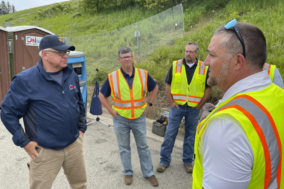 Minnesota Gov. Tim Walz, left, speaks to Blue Earth County Public Works Director Ryan Thilges, far right, about the status of the Rapidan Dam and a nearby bridge, Tuesday, July 2, 2024, in Rapidan, Minn. (AP Photo/Michael Goldberg)