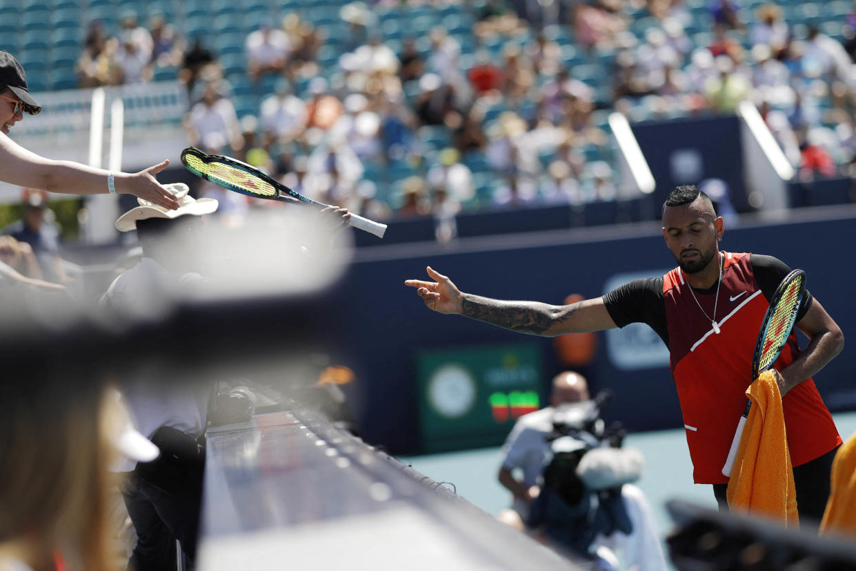 Mar 29, 2022; Miami Gardens, FL, USA; Nick Kyrgios (AUS) tosses his smashed racquet to a fan in the stands between games against Jannik Sinner (ITA)(not pictured) in a fourth round men's singles match in the Miami Open at Hard Rock Stadium. Mandatory Credit: Geoff Burke-USA TODAY Sports