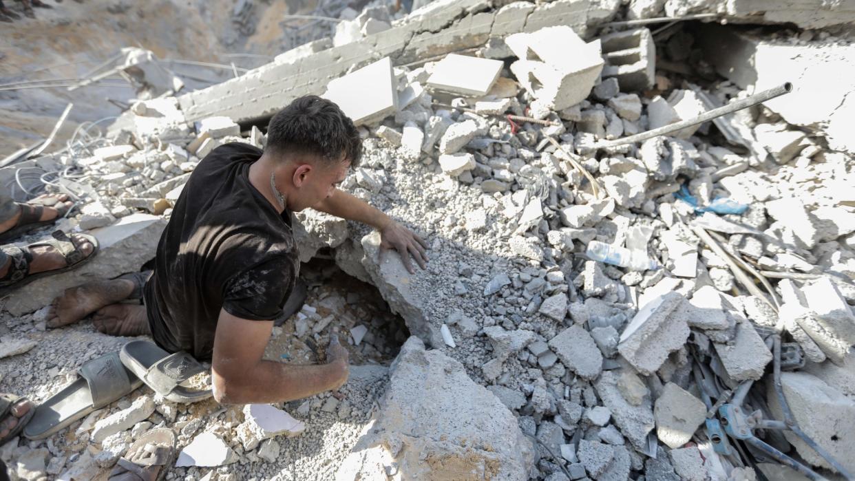  A man searches through rubble in Gaza. 