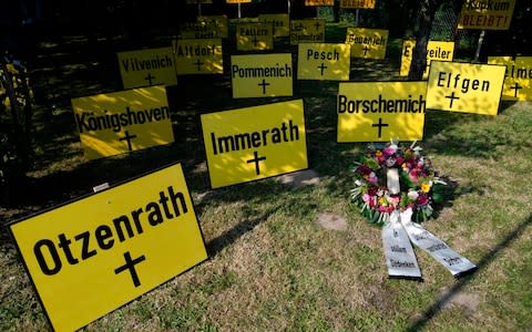 Signs reading the names of relocated villages are seen in a garden near the open-cast mines of Garzweiler near Keyenberg, western Germany, - Credit: INA FASSBENDER