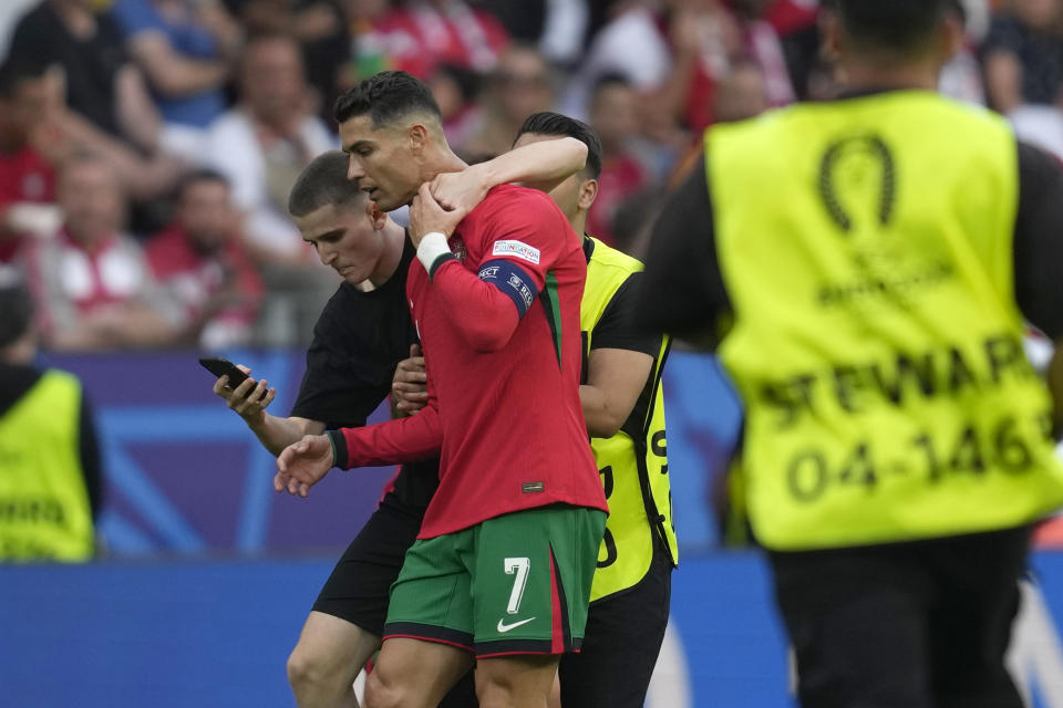 A pitch invader tries to take a selfie with Portugal's Cristiano Ronaldo as a steward moves him out during a Group F match between Turkey and Portugal at the Euro 2024 soccer tournament in Dortmund, Germany, Saturday, June 22, 2024. (AP Photo/Darko Vojinovic)