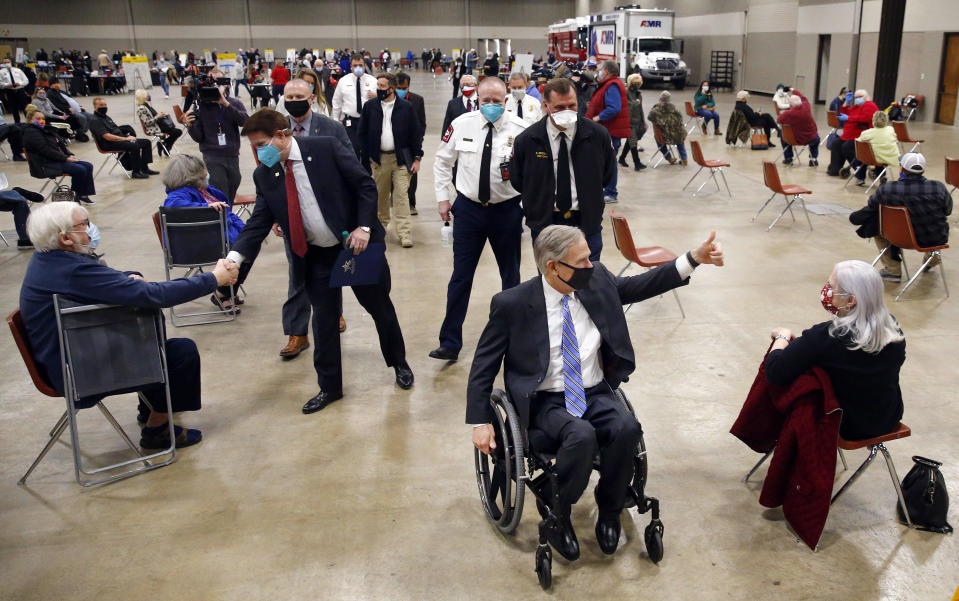 Texas Governor Greg Abbott gives a thumbs up to people who received a COVID-19 shot as he tours a mass vaccination site inside Esports Stadium Arlington & Expo Center in Arlington, Texas, Monday, January 11, 2021.  / Credit: Tom Fox / AP