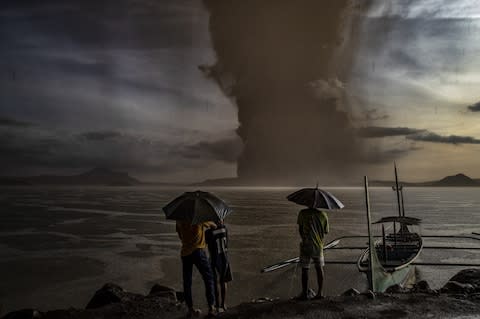 Residents look on as Taal Volcano erupts on January 12, 2020 in Talisay, Batangas province, Philippines - Credit: Ezra Acayan