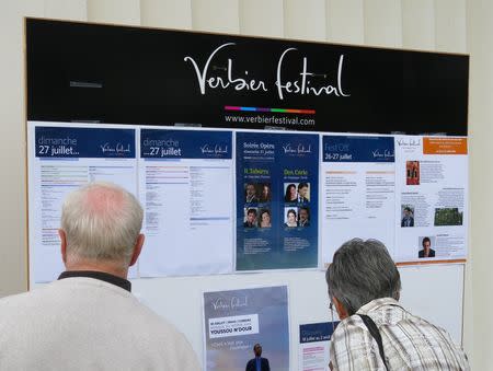 Festivalgoers look at a noticeboard listing details of the day's events at the Verbier Festival, July 27, 2014. Picture taken July 27, 2014. REUTERS/Michael Roddy