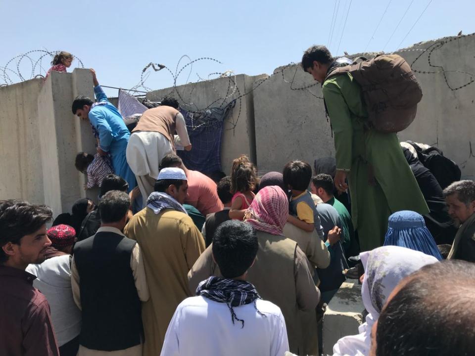 People struggle to cross the boundary wall of Hamid Karzai International Airport to flee the country. Source: Getty