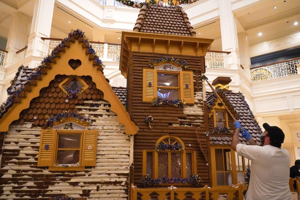 A Disney cast member scrapes the gingerbread off a giant house that was on display through the holidays at the Grand Floridian Resort and Spa.