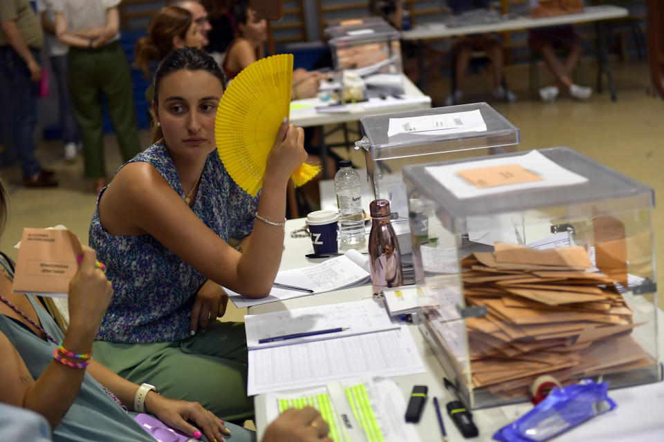 An election official uses a fan as she sits at a polling station in Pamplona, Spain, Sunday July 23, 2023. Spain is holding general elections, that could make the country the latest European Union member to swing to the political right, at the height of summer, when millions of citizens are likely to be vacationing away from their regular polling places.(AP Photo/Alvaro Barrientos)