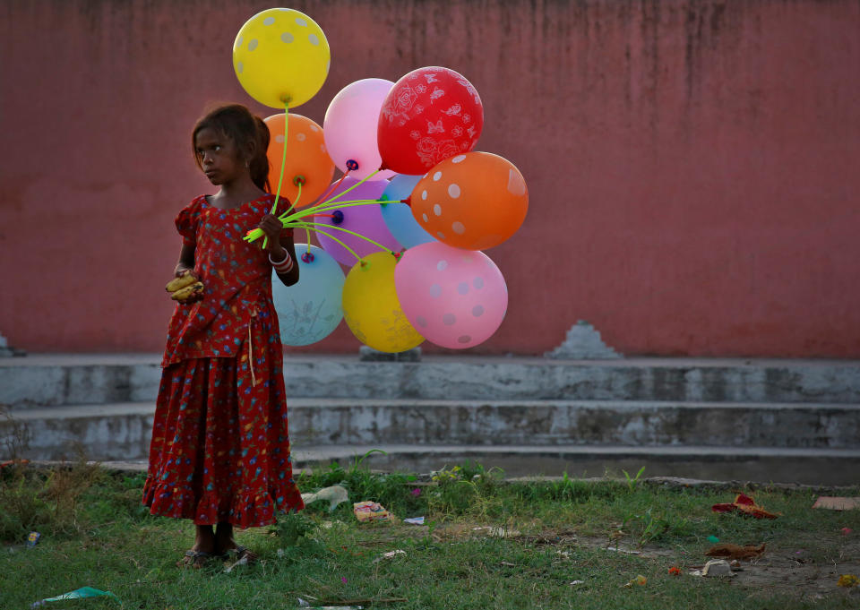 A young girl sells balloons by the Yamuna River on the last day of the Ganesh Chaturthi festival in Delhi, India, on Sept. 15, 2016. (Photo: Cathal McNaughton / Reuters)