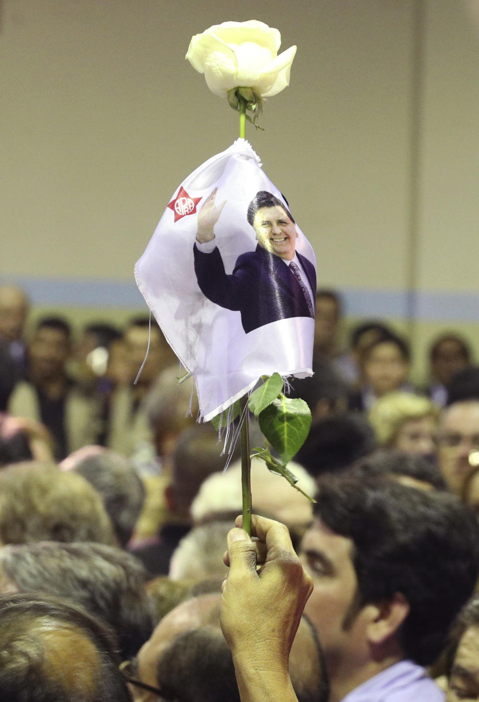 Una persona sostiene una flor con una foto del fallecido expresidente de Perú, Alan García, durante su velatorio en la sede de su partido en Lima, el miércoles 17 de abril de 2019. (AP Foto / Martín Mejía)