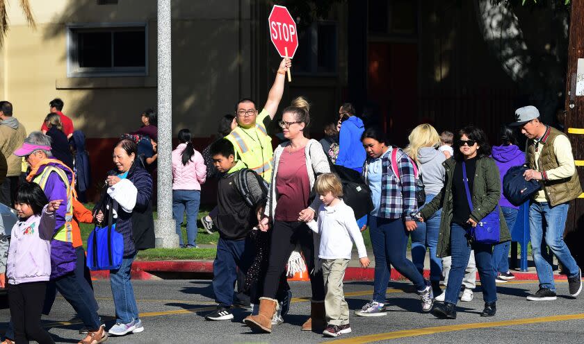 An Alhambra Unified School District crossing guard stops traffic for parents picking up their children from Ramona Elementary School on February 4, 2020 in Alhambra, California. - As the coronavirus outbreak spreads, fuelling rumors and misinformation, a petition to cancel all classes in one US school district for fear of the virus has garnered nearly 14,000 signatures. The online petition posted on Change.org urges the Alhambra Unified School District located east of Los Angeles and with a heavily Asian population, to basically shut down until the outbreak is over. School district officials, however, have dismissed the petition as a bid to whip up hysteria over the deadly outbreak that has killed hundreds in China. (Photo by Frederic J. BROWN / AFP) (Photo by FREDERIC J. BROWN/AFP via Getty Images)