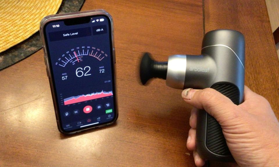 A massage gun shown with a noise-meter app.