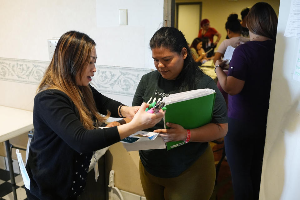 Image: A volunteer checks in an attendee during an orientation session for recent immigrants (David Zalubowski / AP)