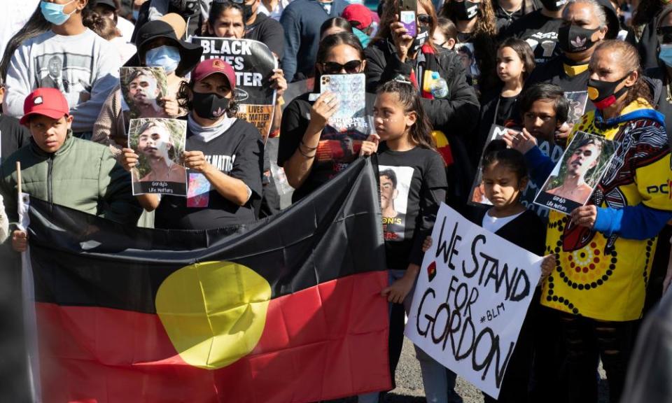 Demonstrators with an Aboriginal flag and signs at the rally