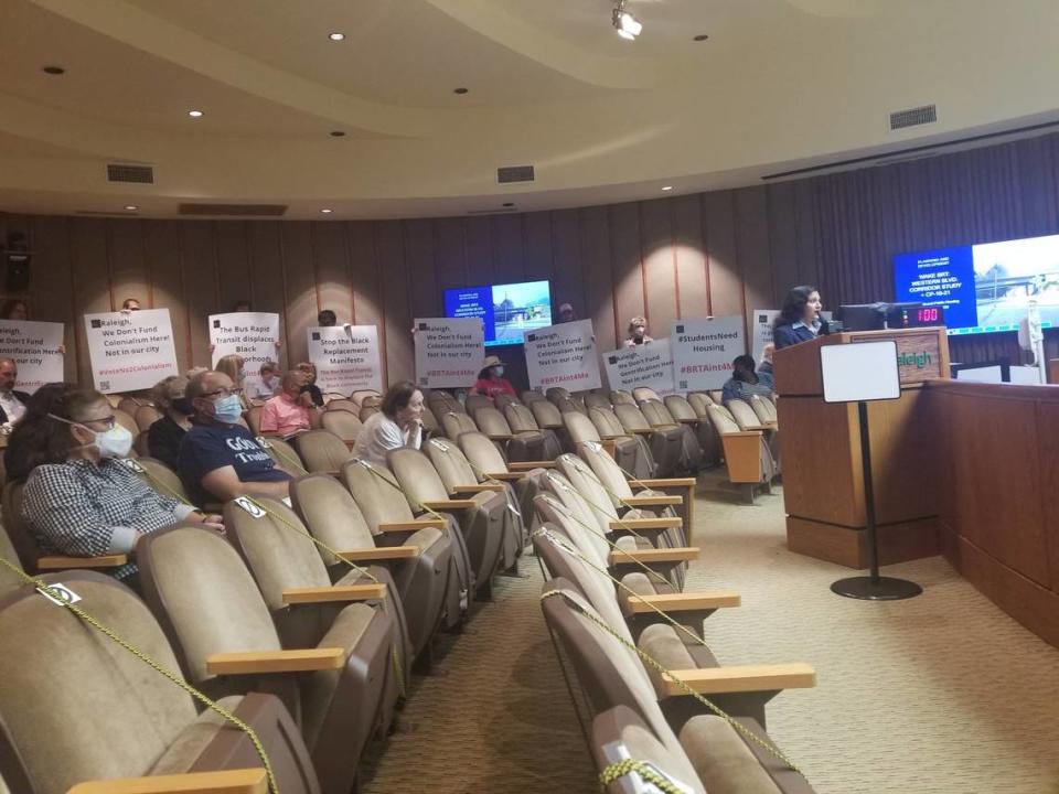 People hold signs during a June 7, 2022, Raleigh City Council meeting.
