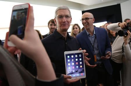 Apple CEO Tim Cook holds a new iPad after a presentation at Apple headquarters in Cupertino, California October 16, 2014. REUTERS/Robert Galbraith