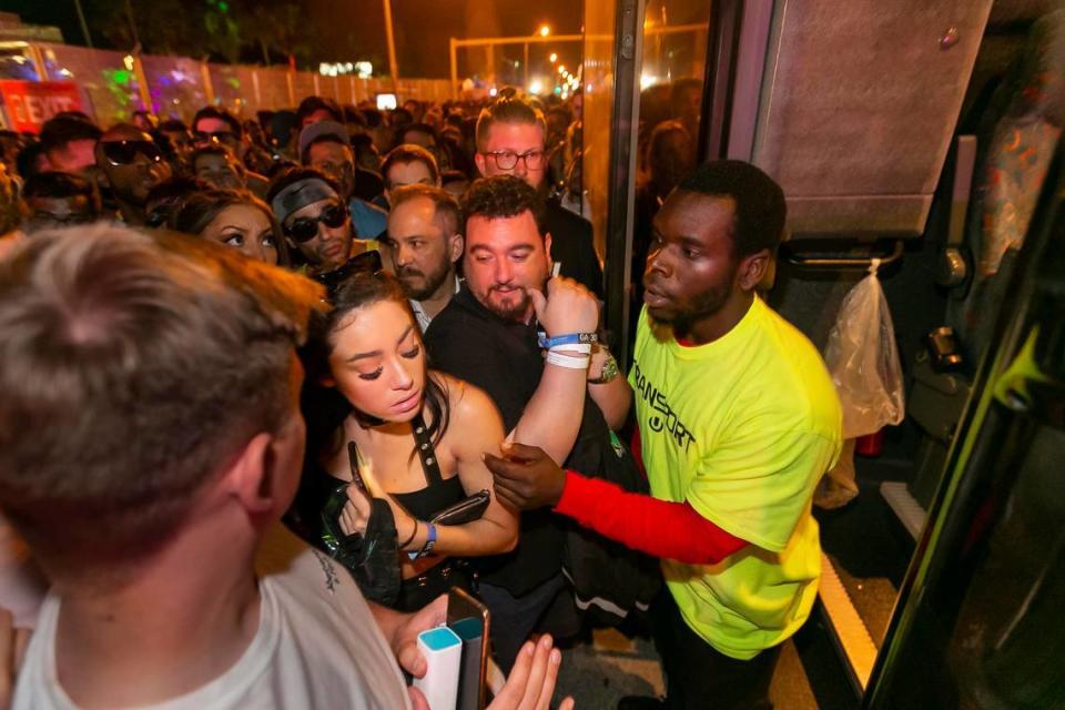 Maurice Williams, de 22 años, a la derecha, trata de lidiar con las personas que intentan subir a un autobús mientras los asistentes salen del Festival Ultra en Virginia Key, Florida el 30 de marzo de 2019.