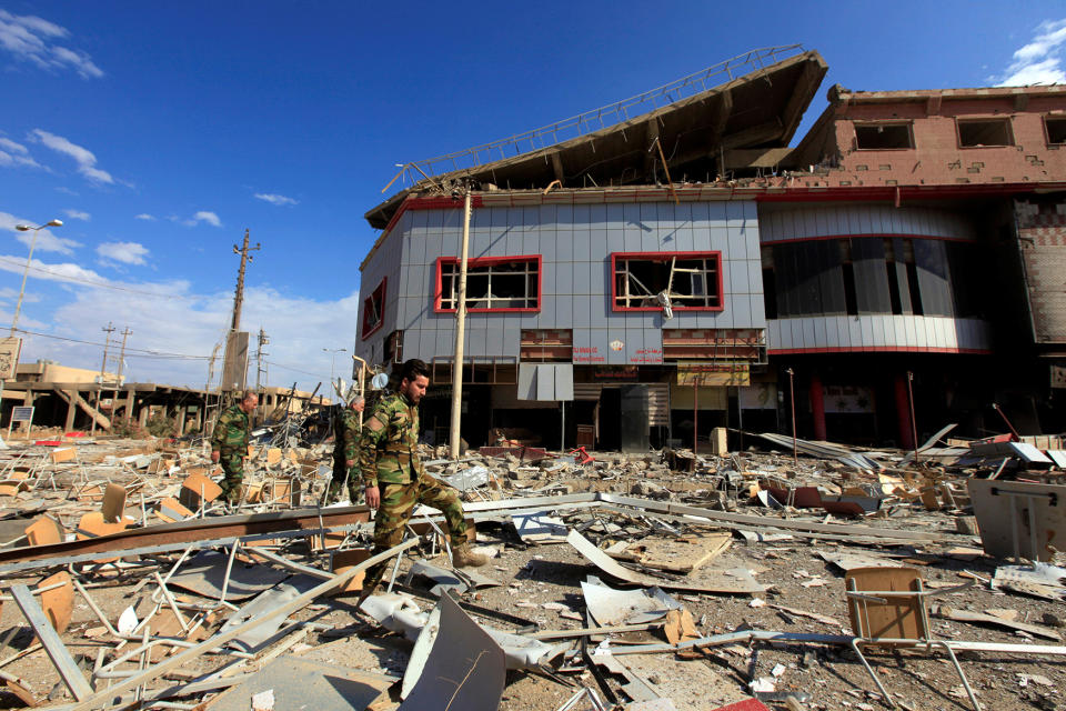 Iraqi Christian soldiers walk near a building destroyed by ISIS militants