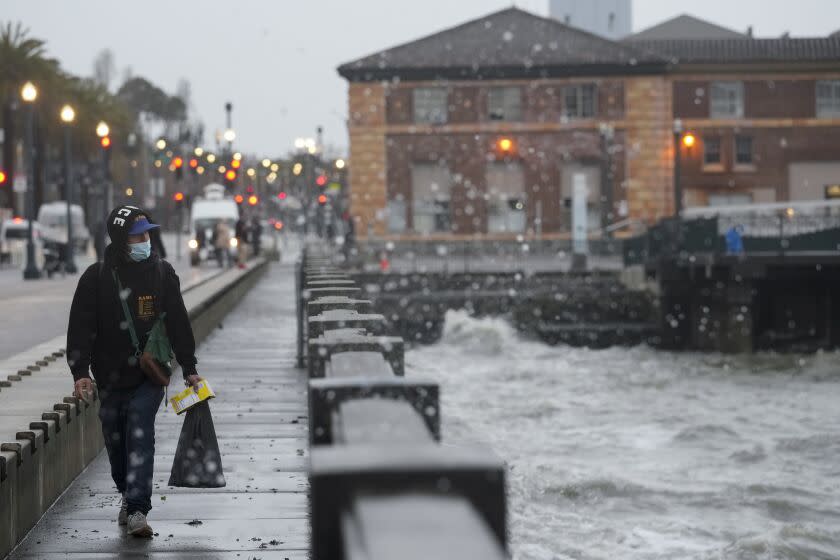 A person walks along The Embarcadero in San Francisco, Wednesday, Jan. 4, 2023. Another winter storm is expected to move into California on Wednesday, walloping the northern part of the state with more rain and snow. It's the second major storm of the week in the parched state. It follows storms that brought threats of flash flooding and severe thunderstorms across the southern U.S. and heavy snow in the upper Midwest. (AP Photo/Godofredo A. Vásquez)