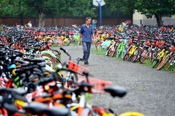 HEFEI, CHINA - AUGUST 16: A man walks by the rental bikes detained by the local urban administration authority of Luyang district  in Anhui province on August 16, 2017 in Hefei, China. Tens of thousands of rental bikes parked at spots causing troubles to pedestrians and traffic in streets have been removed away by government authorities to the graveyards of the bikes while bike companies struggle to regulate the parking behavior of their users. PHOTOGRAPH BY Feature China / Barcroft Images London-T:+44 207 033 1031 E:hello@barcroftmedia.com - New York-T:+1 212 796 2458 E:hello@barcroftusa.com - New Delhi-T:+91 11 4053 2429 E:hello@barcroftindia.com www.barcroftimages.com (Photo credit should read Feature China / Barcroft Images / Barcroft Media via Getty Images)