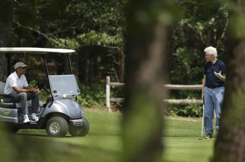 President Barack Obama, left, sits in a cart while talking with former President Bill Clinton, right, as they golf Saturday, Aug. 15, 2015, at Farm Neck Golf Club, in Oak Bluffs, Mass., on the island of Martha's Vineyard. (AP Photo/Steven Senne)