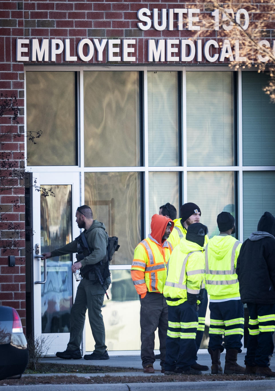 City employees and a police officer with the Winston-Salem Police Department stand outside of the Joycelyn V. Johnson Municipal Services Center after reports of gunshots in Winston-Salem, N.C. early Friday, Dec. 20, 2019. Winston- Salem Police are confirming there was a shooting but are not saying at this time if there are any injuries or deaths. (Andrew Dye/The Winston-Salem Journal via AP)