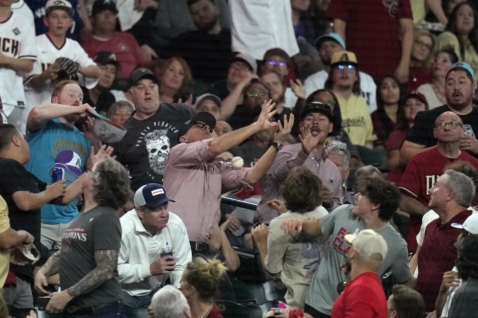 Fans go after a foul ball hit by Colorado Rockies' Michael Toglia during the eighth inning of the team's baseball game against the Arizona Diamondbacks on Thursday, March 28, 2024, in Phoenix. The Diamondbacks won 16-1. (AP Photo/Ross D. Franklin)