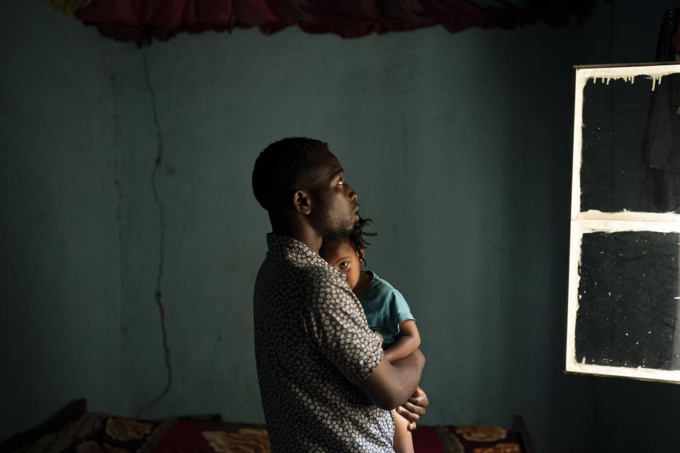 In this Sept. 9, 2019 photo, Emmanuel Bizimana holds 2-year-old Blessing, whose mother, Sandrine Umwungeri, passed away recently, as a health worker conducts a "verbal autopsy" in Kigali, Rwanda. Increasingly health officials worldwide are trusting these tools, which are analyzed by computer algorithms, to learn more about global course of human disease. (AP Photo/Felipe Dana)