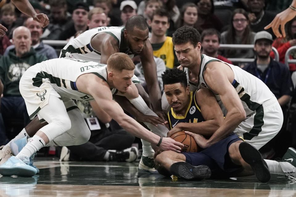 Indiana Pacers' Malcolm Brogdon battles for a loose ball with Milwaukee Bucks' Donte DiVincenzo, Khris Middleton and Brook Lopez during the second half of an NBA basketball game Sunday, Dec. 22, 2019, in Milwaukee. The Bucks won 117-89. (AP Photo/Morry Gash)