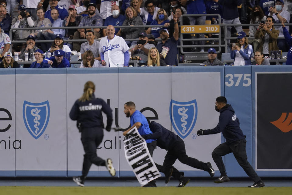 A fan who made his way on to the field is tackled by security personnel during a baseball game between the Arizona Diamondbacks and the Los Angeles Dodgers Wednesday, Sept. 15, 2021, in Los Angeles. (AP Photo/Ashley Landis)