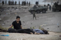 Men sit on the ground after arriving in the Spanish territory at the border of Morocco and Spain, at the Spanish enclave of Ceuta, on Tuesday, May 18, 2021. Ceuta, a Spanish city of 85,000 in northern Africa, faces a humanitarian crisis after thousands of Moroccans took advantage of relaxed border control in their country to swim or paddle in inflatable boats into European soil. Around 6,000 people had crossed by Tuesday morning since the first arrivals began in the early hours of Monday, including 1,500 who are presumed to be teenagers. (AP Photo/Javier Fergo)