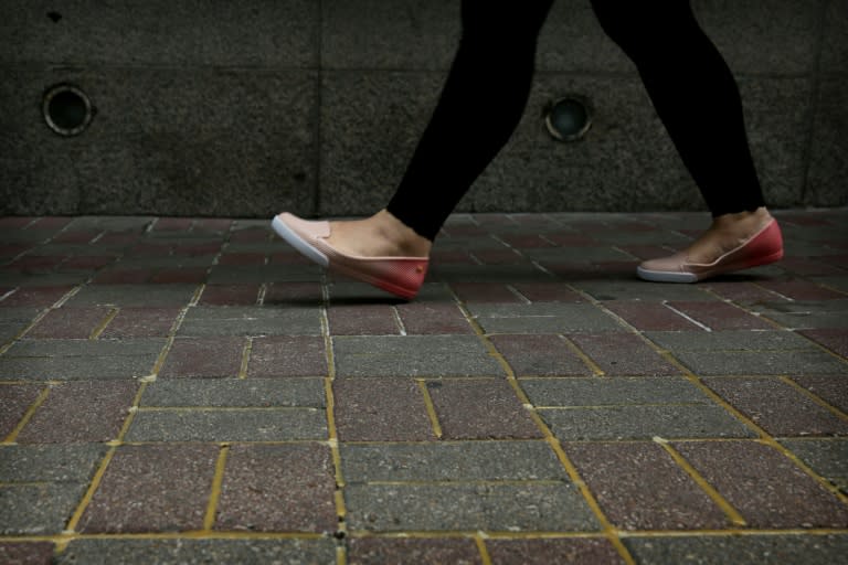 A woman walks over pavement reinforced with glue to prevent the bricks from being dug up and used as projectiles during expected protests in Hong Kong