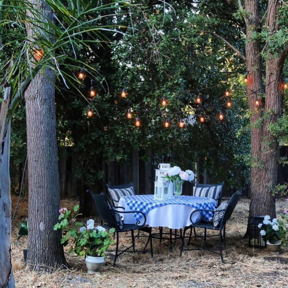 <p>If you’re working with a wooded backyard, make use of nature and string lights from the branches. Place a table and chairs underneath for the perfect summertime dinner party setup.</p><p><strong>See more at <a href="https://www.instagram.com/p/B0mkHxgAKxT/?igshid=1f89v5fb2zp7j" rel="nofollow noopener" target="_blank" data-ylk="slk:jodie.thedesigntwins;elm:context_link;itc:0;sec:content-canvas" class="link ">jodie.thedesigntwins</a>.</strong></p><p><a class="link " href="https://www.amazon.com/Outdoor-Commercial-Waterproof-Dimmable-Backyard/dp/B07HSYVD1M/?tag=syn-yahoo-20&ascsubtag=%5Bartid%7C10050.g.31137877%5Bsrc%7Cyahoo-us" rel="nofollow noopener" target="_blank" data-ylk="slk:SHOP STRING LIGHTS;elm:context_link;itc:0;sec:content-canvas">SHOP STRING LIGHTS</a></p>