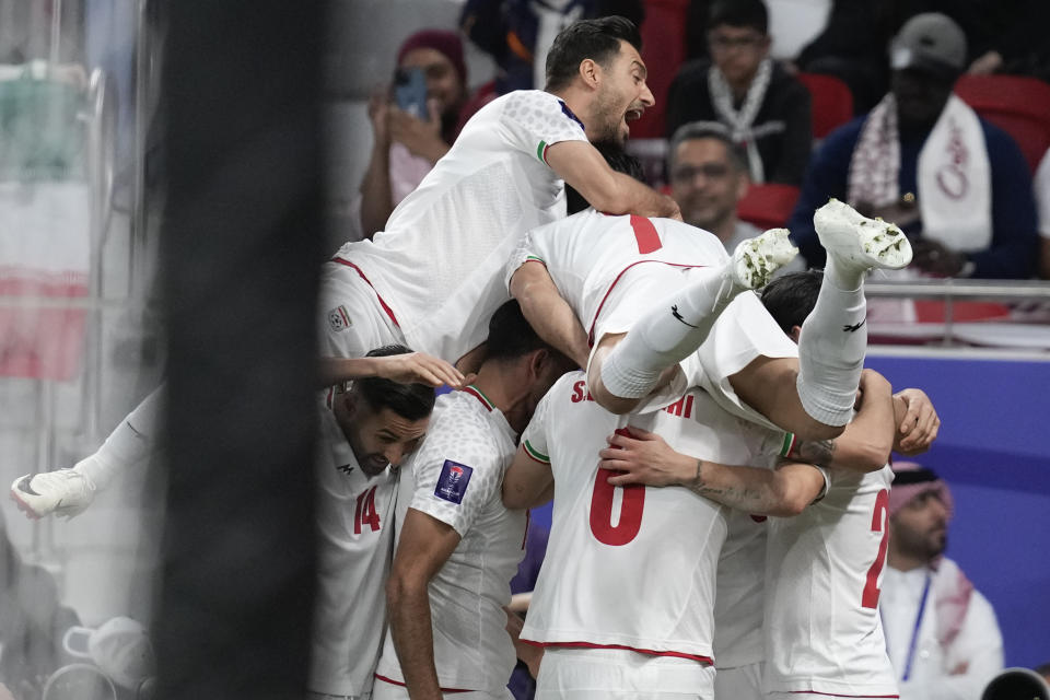 Iran's Sardar Azmoun, right, celebrates with teammates after scoring the first goal during the Asian Cup semifinal soccer match between Qatar and Iran at Al Thumama Stadium in Doha, Qatar, Wednesday, Feb. 7, 2024. (AP Photo/Thanassis Stavrakis)