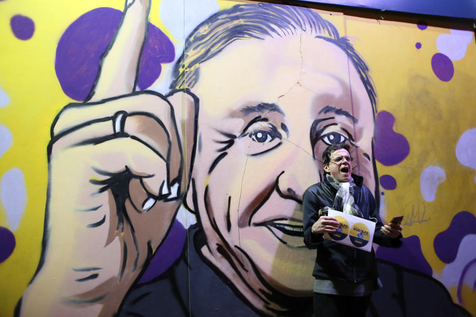 A supporter of Rodolfo Hernandez, presidential candidate with the Anti-corruption Governors League, celebrates in front of a mural of the candidate on election night in Bogota, Colombia, Sunday, May 29, 2022. Hernandez will advance to a runoff contest in June after none of the six candidates in Sunday's first round got half the vote. (AP Photo/Leonardo Munoz)