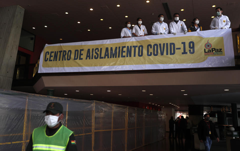 A policeman stands guard as doctors wait for the arrival of people with "mild or suspected cases" of the new coronavirus to the Center of Isolation in the Hotel Real Plaza, in La Paz, Bolivia, Thursday, April 16, 2020. The government has authorized the former Radisson hotel as a quarantine center to treat people with "mild or suspected cases" of COVID-19, said Bolivia's interim president. (AP Photo/Juan Karita)